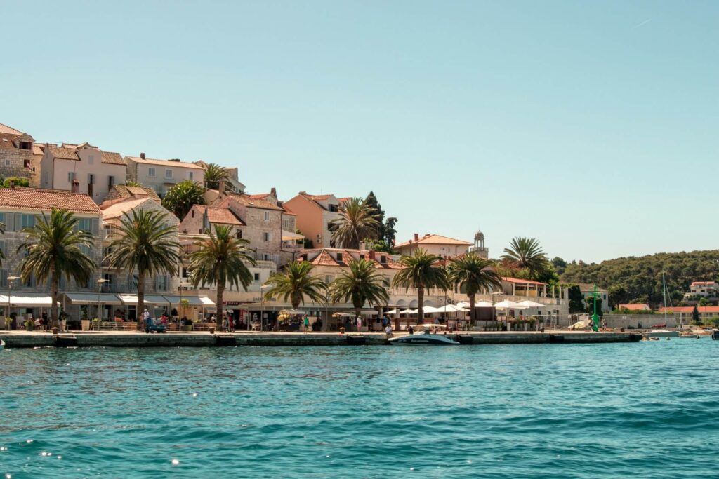 Hvar waterfront promenade with palm trees and stone buildings along the Adriatic coast