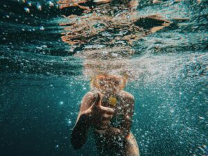 Person snorkeling underwater in clear blue Adriatic Sea, showing thumbs up with bubbles all around