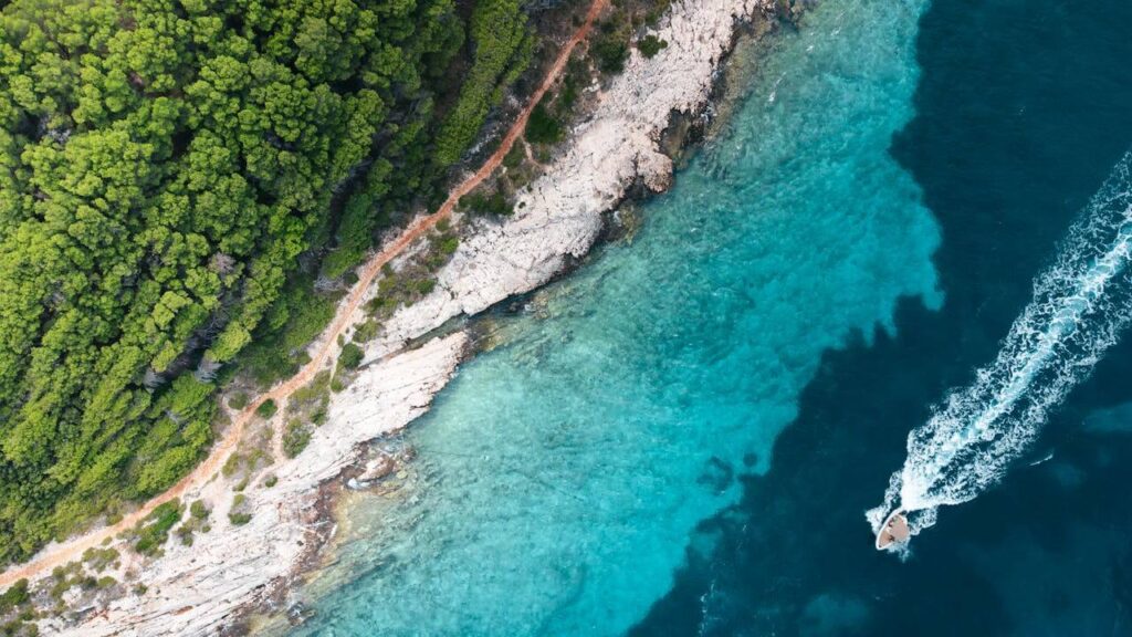 An image of the sea coast, showing the clear blue sea and a yacht